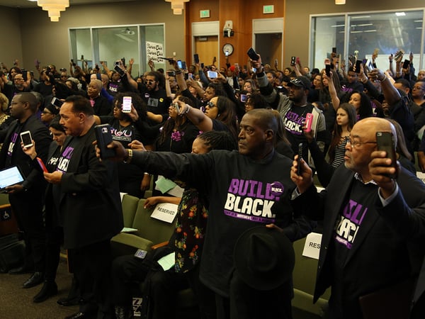Attendees hold up cell phones in protest at the community forum on the police shooting of Stephon Clark March 27, 2018.
